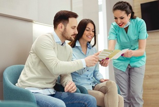 dental team member showing paperwork to two patients