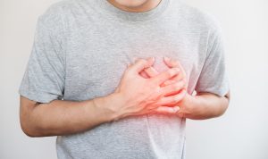 Man in grey shirt with hand over heart; chest pain