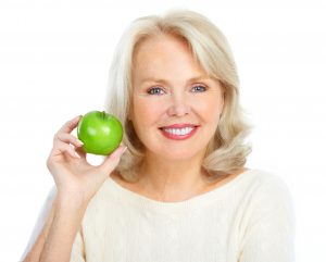 woman smiling while holding apple