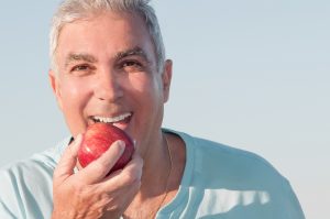 older man smiles holding apple